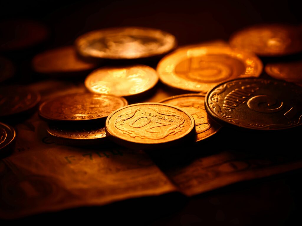 A detailed close-up of various coins illuminated with warm lighting, symbolizing wealth and savings.
